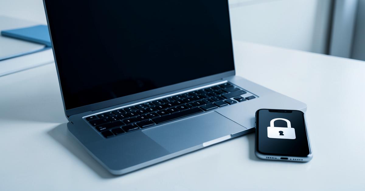 Laptop and phone on a white desk with a padlock icon on the phone screen